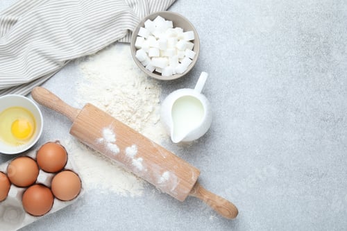 Preview: Rolling pin and ingredients for dough on light grey table, flat lay. Space for text