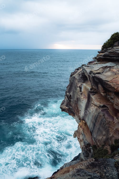 Preview: Vertical shot of a cliff and the blue sea on a cloudy day