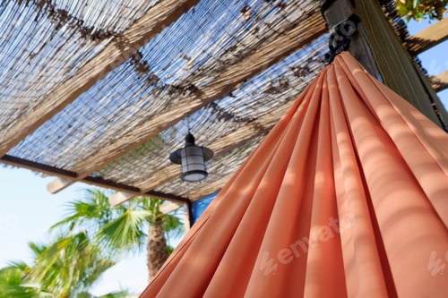 Preview: A red hammock hangs in the shade of a porch in summer.