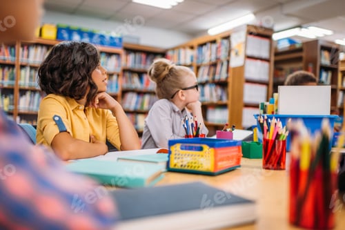 Preview: adorable little kids sitting at desk in library