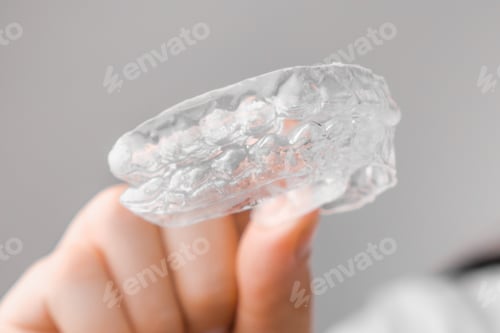 Preview: Close up of clear aligners in hand of woman. Orthodontic treatment for whitening and straightening