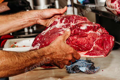 Preview: A man holding a large piece of raw red meat
