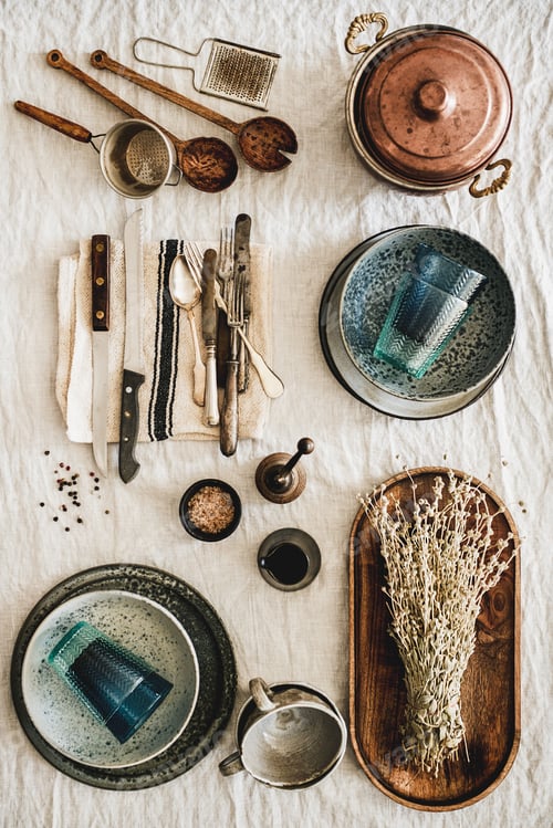 Preview: Various kitchen utensils and tablewear over linen tablecloth, vertical composition
