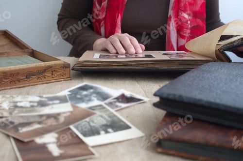 Preview: Midsection of woman holding vintage photo album and watching black and white photos