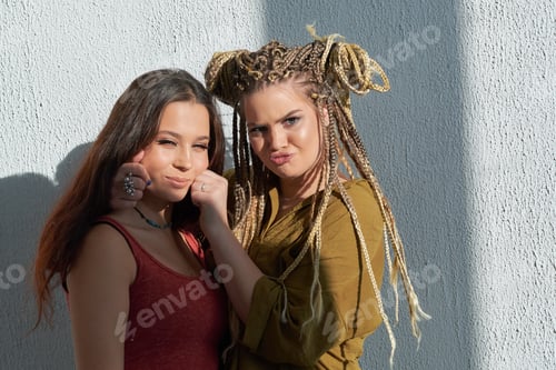 Preview: best friends hugging against a white wall. bright sunlight, contrast light.