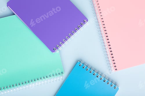 Preview: colored notebooks, colored pencils on a light table. Place for your text.
