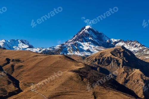 Preview: A picturesque scene of snow-capped summits under the endless expanse of a deep blue sky.