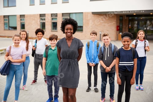 Visualização: Retrato de um grupo sorridente de estudantes do ensino médio com uma professora do lado de fora dos prédios escolares