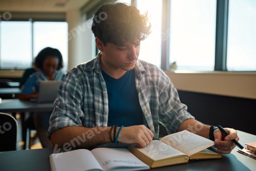 Preview: Young student reading from a book while learning at university classroom.