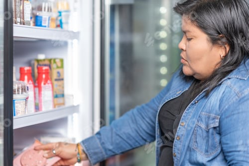 Preview: Woman buying cured meats in a supermarket