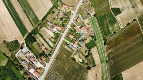 Preview: Arial shot of a huge green farm with plowed land and a small village in the middle of it