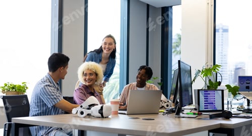 Preview: In modern office, diverse young team laughing around desk