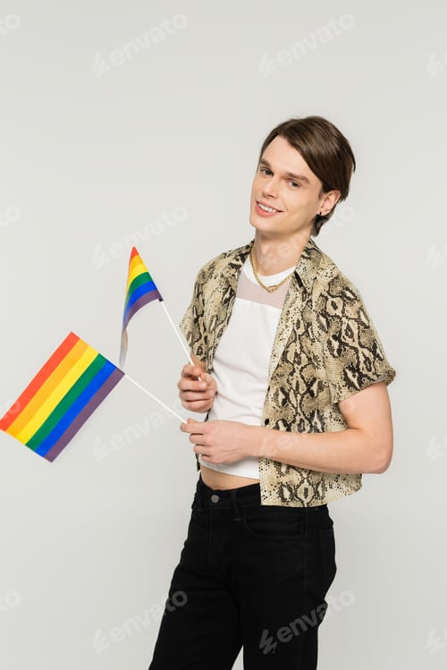 Preview: happy bigender person in snakeskin print blouse holding small lgbt flags isolated on grey