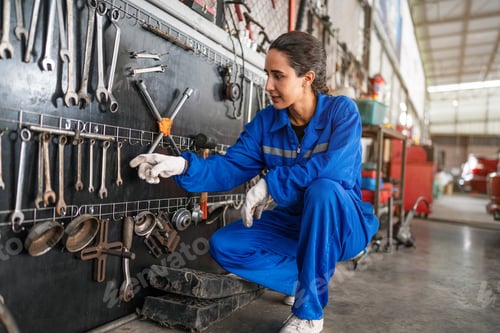 Preview: Portrait of woman auto mechanic working at car repair shop with looking at camera.