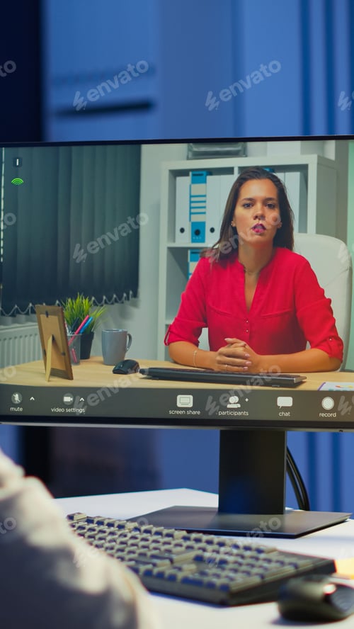 Preview: Manager talking with coworker during video conference at midnight