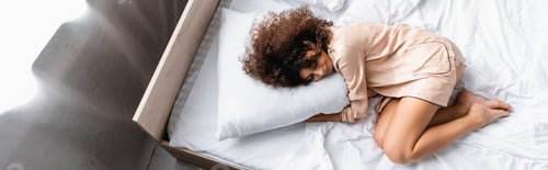 Preview: panoramic concept of barefoot woman with closed eyes hugging pillow while sleeping on bed