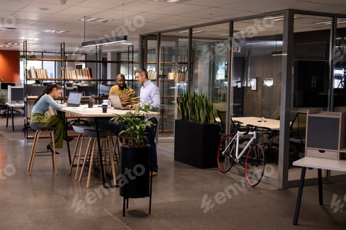 Preview: Multiracial businessmen discussing during meeting by businesswoman working at modern office