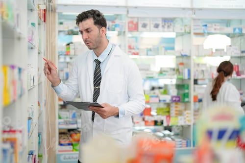 Preview: pharmacist wearing lab coat carefully selects medication in a pharmacy.