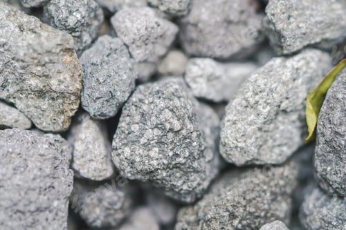 Preview: Pile of pebble stones and gray rocks texture pattern with yellow leaf on the ground in the garden.