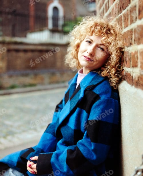 Preview: Classic portrait of curly woman looking camera outdoors.