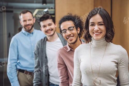 Preview: group of successful businesspeople standing in row and looking at camera at office