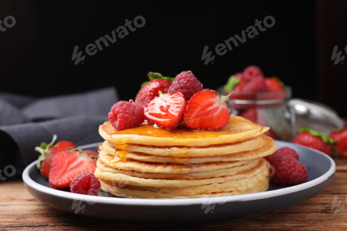 Preview: Tasty pancakes with fresh berries and honey on wooden table, closeup