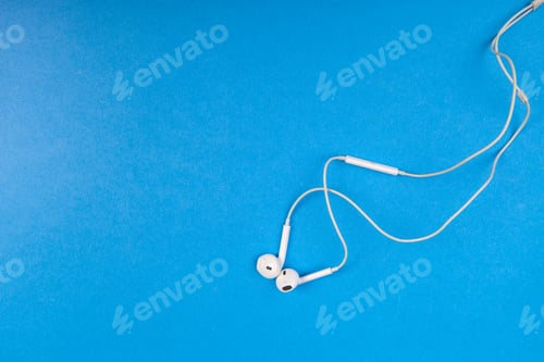 Preview: Earphones on blue background with tangled wires and clear space around them