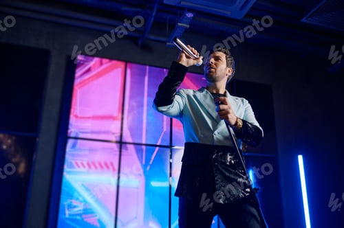 Preview: Male singer holding microphone standing and performing on stage