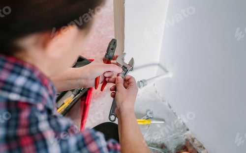 Preview: Female plumber adjusting spanner to install heating