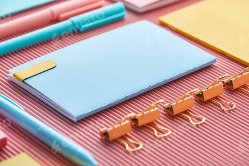 Preview: selective focus of notebook, paper clips and colorful stationery supplies on pink