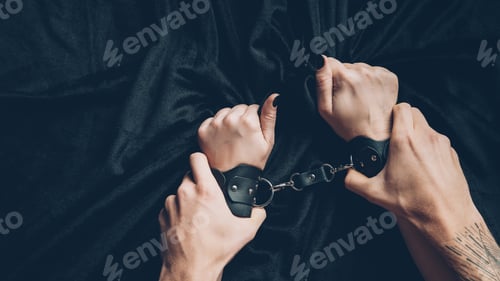 Preview: cropped shot of man holding hands of partner in leather handcuffs
