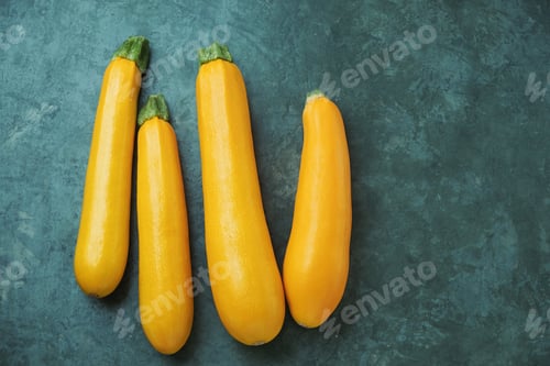 Preview: Four yellow zucchini on kitchen table. Whole raw courgettes