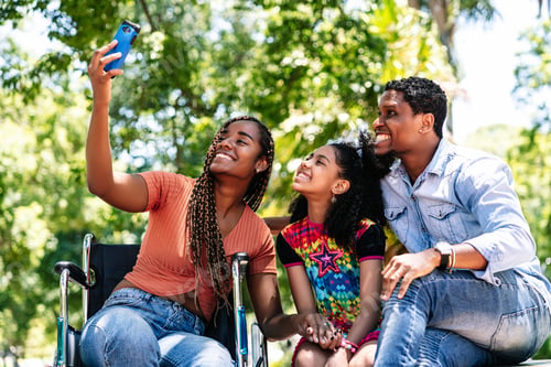 Preview: Woman in a wheelchair taking a selfie with her family.