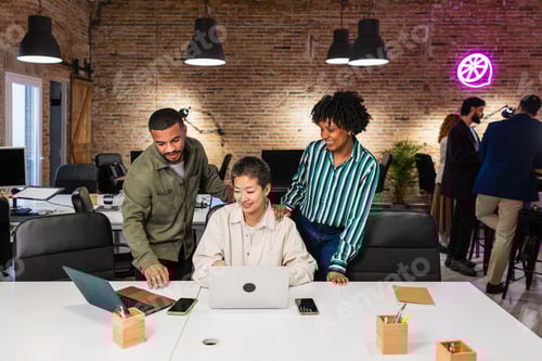 Preview: Multi ethnic team collaborating on laptop in modern office