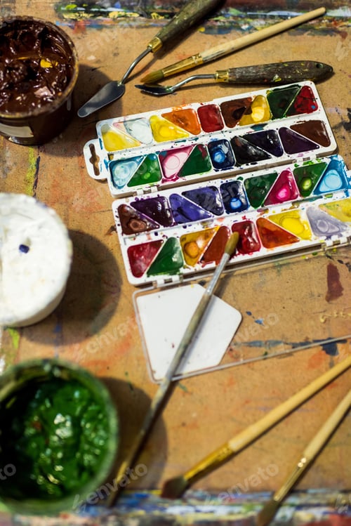 Preview: high angle view of poster paints and watercolor paints on wooden table in workshop