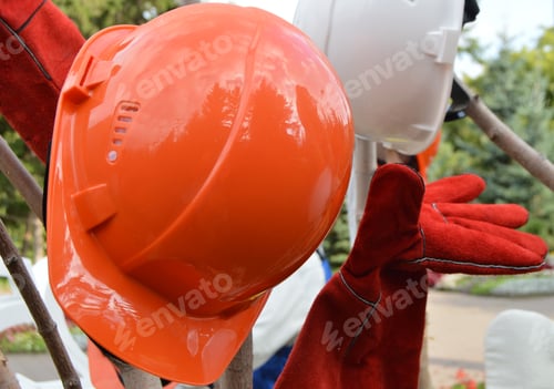 Preview: Closeup of a red protective helmet and gloves, outdoor