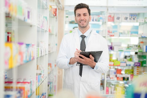 Preview: pharmacist wearing lab coat carefully selects medication in a pharmacy.