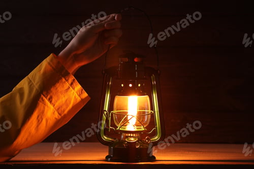Preview: Man with vintage kerosene lamp on wooden background, closeup