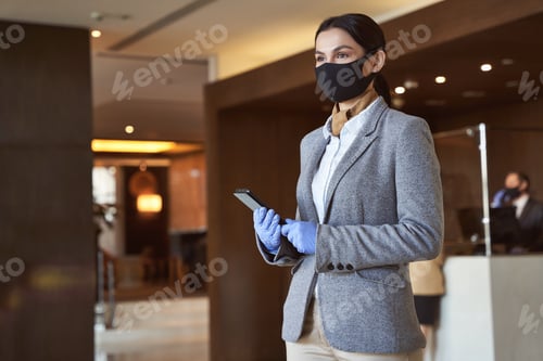 Preview: Receptionist with modern gadget wearing rubber gloves and mask