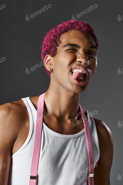 Preview: portrait of playful young man sticking out his tongue in front of camera, fashion and style