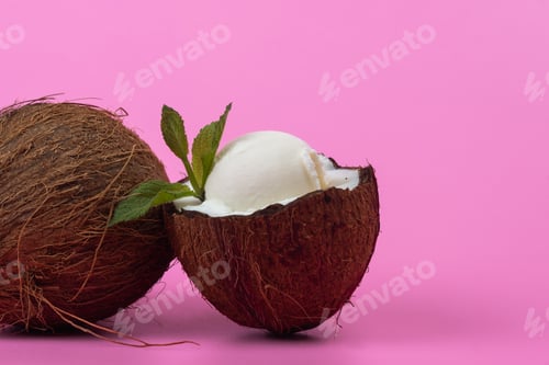 Preview: Vanilla ice cream balls in fresh coconut halves decorated with mint leaves on a pink background