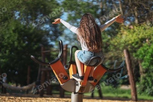 Preview: Caucasian beautiful girl spinning swing in the park at the playground