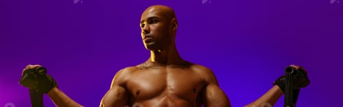 Preview: Sporty man performs exercises with expander on violet studio background. Strength and motivation