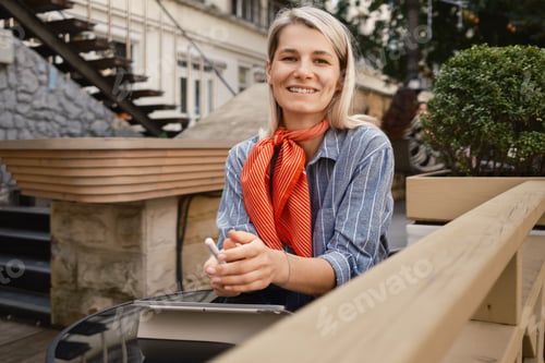 Preview: Smiling woman sitting at outdoor cafe