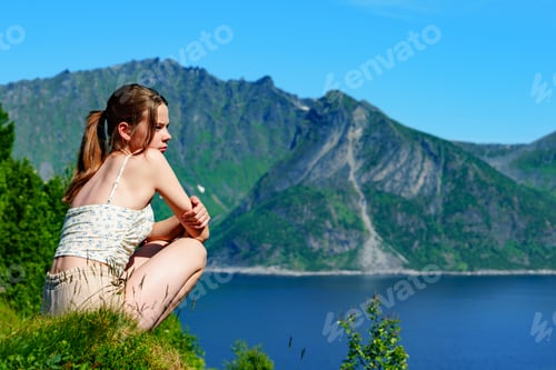 Vista previa: A girl sitting on the top of the mountain and enjoying Norway view above sea and mountains.