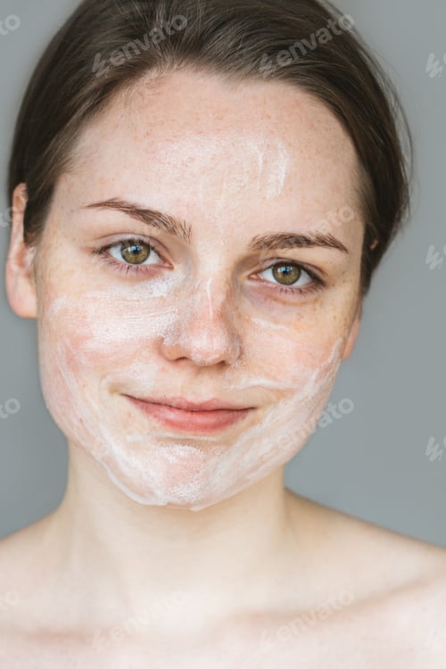 Preview: Young beautiful woman washing her face with hands by soap. Studio shot