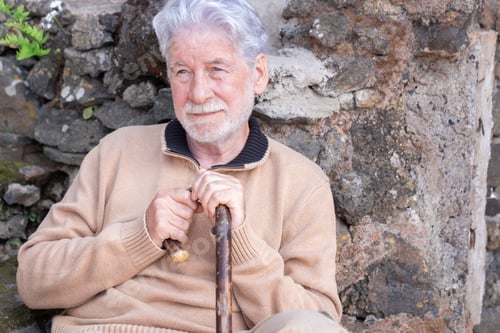 Preview: Portrait of relaxed bearded senior man sitting outdoors home holding a walking cane