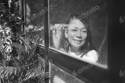 Preview: Black and white portrait of happy senior woman near window.