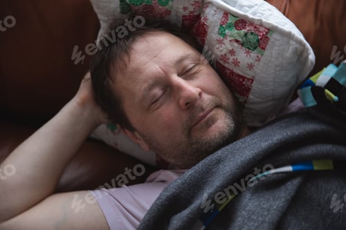 Preview: Relaxed man resting on a couch at home