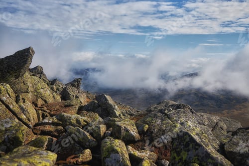 Preview: Clouds hover over rocky landscape in high mountains during the day